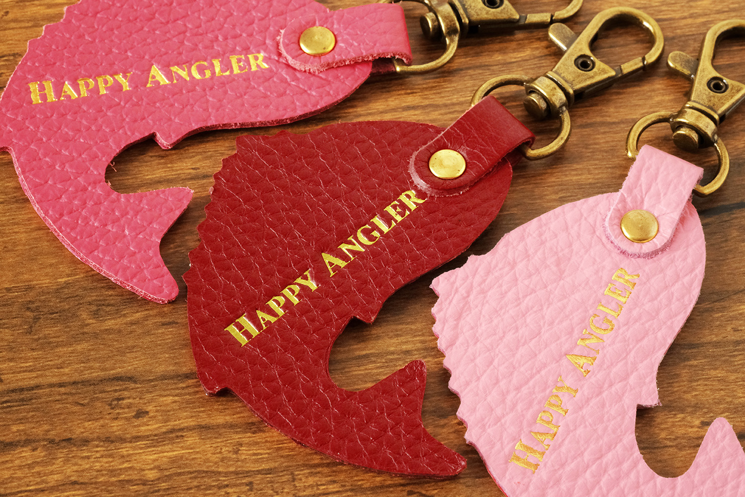 「HAPPY ANGLER リアル魚皮キーホルダー」の「シェイプ：跳ねるマダイ」の裏面の写真。「HAPPY ANGLER」の文字が刻印されている。