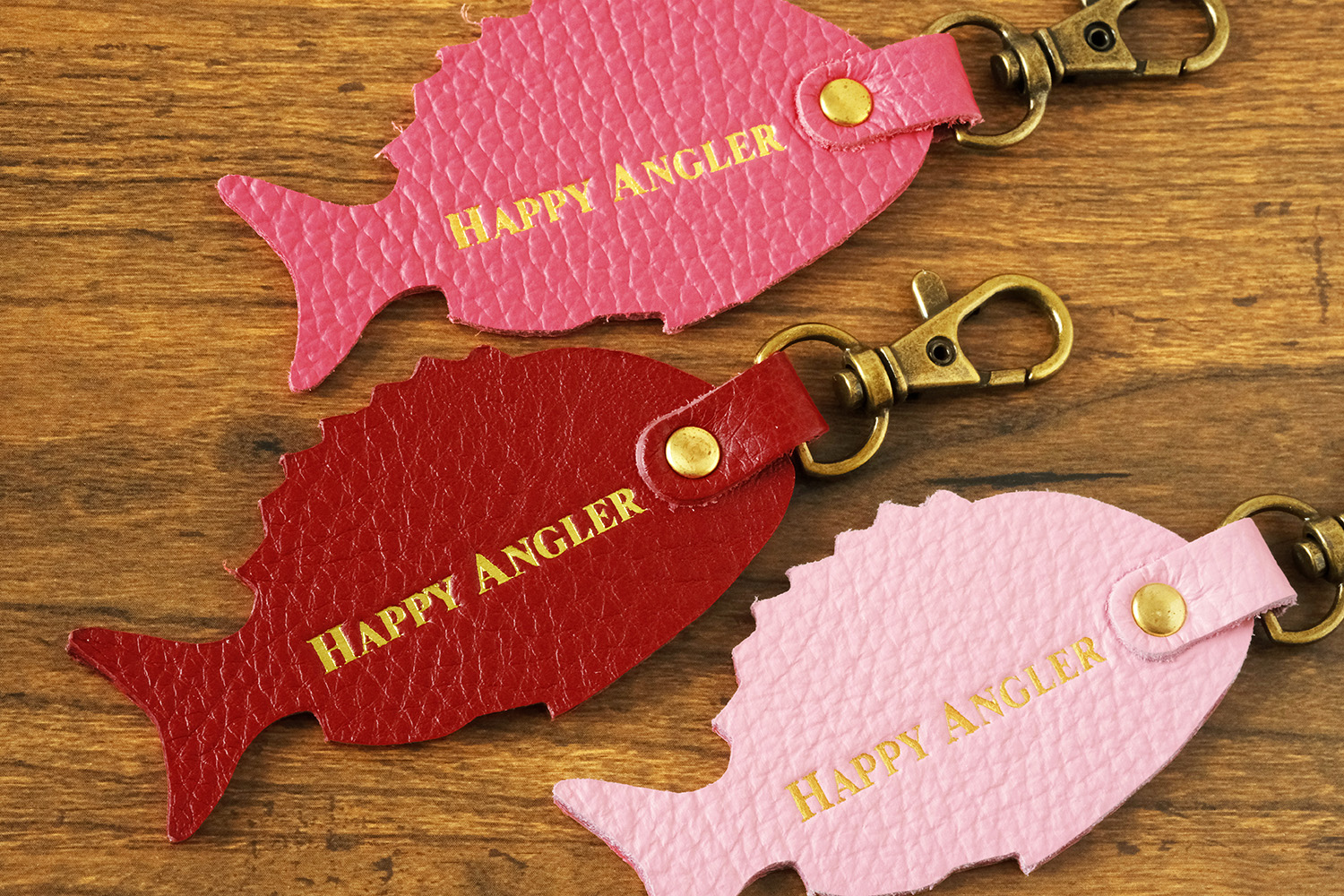 「HAPPY ANGLER リアル魚皮キーホルダー」の「シェイプ：マダイ」の裏面の写真。「HAPPY ANGLER」の文字が刻印されている。