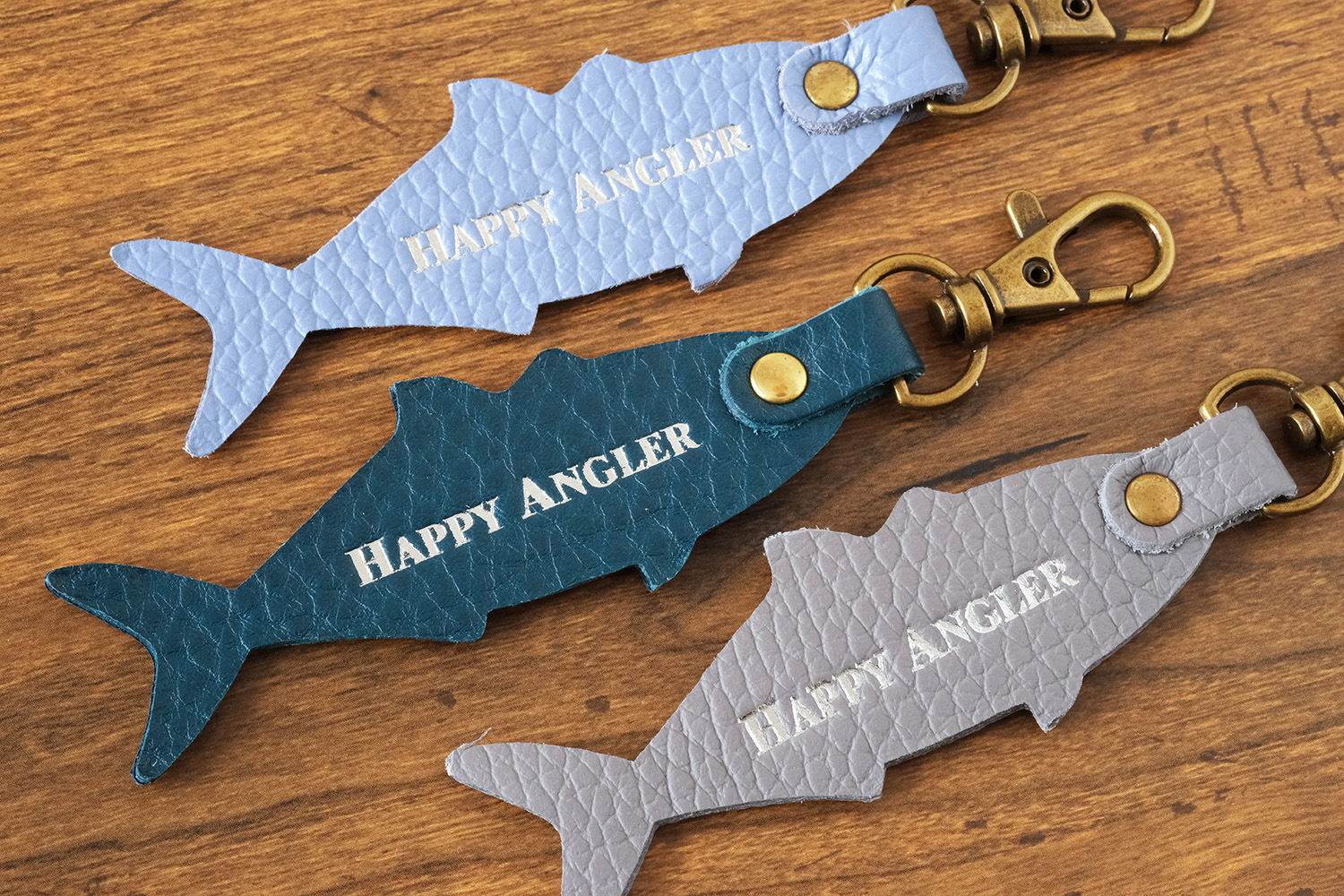 「HAPPY ANGLER リアル魚皮キーホルダー」の「シェイプ：ブリ」の裏面の写真。「HAPPY ANGLER」の文字が刻印されている。